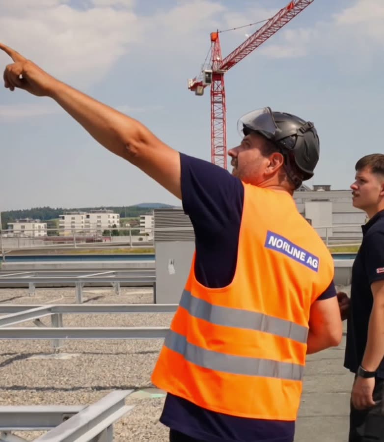 Zwei Monteure auf dem Dach während der Kranmontage
